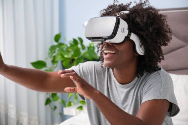 Young african woman experiencing virtual reality on her bed in the morning.