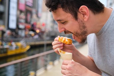 Mitarashi dango yiyen turist, geleneksel Japon pirinç köfteleri soya jölesine bulanmış, caddede..