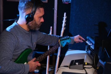 Gitarı karıştırma konsoluna bağlayan müzisyen. Müzik üretimi.
