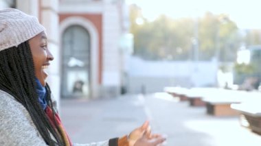 İki çok kültürlü kadın mutlu arkadaş birbirine sarılıyor ve caddede gülümsüyor..