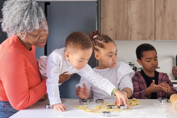 African family cutting cookie shapes in a cookie dough in the kitchen. Horizontal extended family.