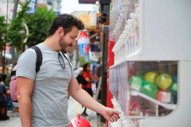 Tokyo, Japonya 'da gazhapon otomatından oyuncak kapsülü alan Latin bir turist.