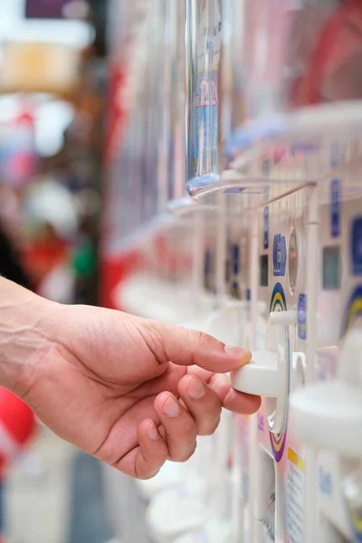 Hand buying a toy capsule at gashapon vending machine in Tokyo, Japan.