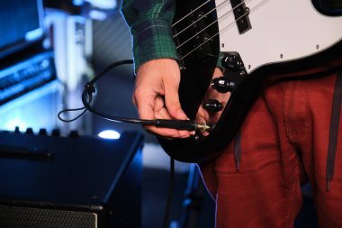 Müzisyen elinin, bas gitarını bir amplifikatöre bağlamasına yakın çekim. Müzik üretimi.