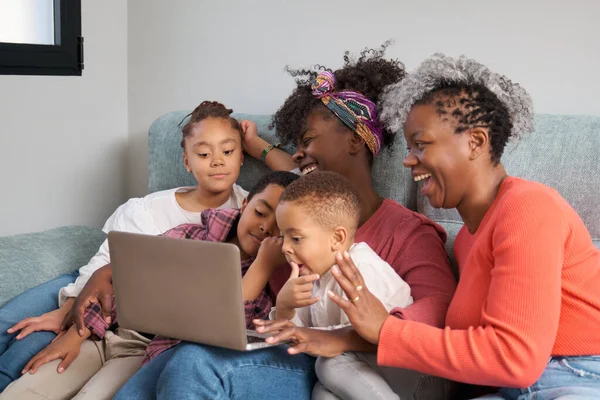 Happy african family laughing and doing a video call on a laptop at home.