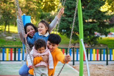 İki çocuklu İspanyol bir aile oyun parkında birlikte oynuyorlar. Latin ailesi.