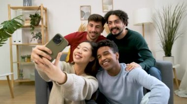 Gülümseyen ve evde selfie çeken çok ırklı arkadaş grubu..