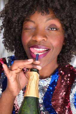 Yeni yıl partisinde bir kamışla şampanya içip gülümseyen bir kadın..