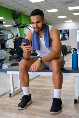 Spor salonunda akıllı telefonuyla müzik dinleyen güçlü bir İspanyol..