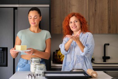 Anne ve kızı bir kurabiye tarifini işaret diliyle açıklıyor. Tereyağı işareti.
