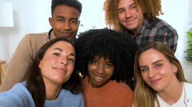 Bir grup çok ırklı mutlu arkadaş evde selfie çekiyor. Gülümseyen insanlar portresi.