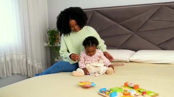 キューバの母親は 赤ちゃんが本で遊んでいる間 ベッドに彼女の幼い娘に服を変える — ストック動画