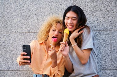 Dondurmalı iki çok ırklı arkadaş yazın sokakta selfie çekiyor..