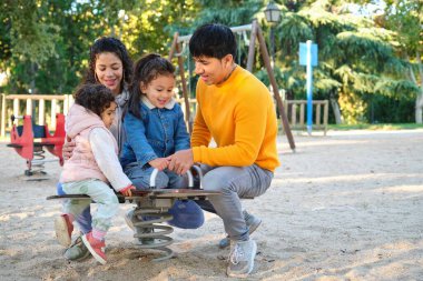 İki çocuklu İspanyol bir aile oyun parkında birlikte oynuyorlar. Latin ailesi.