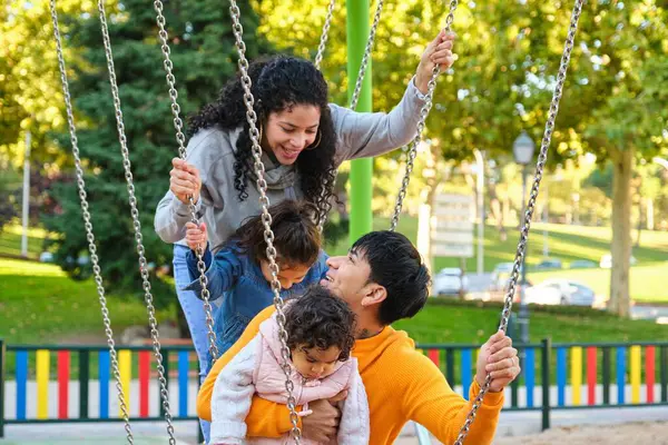 Latin family with two children playing together in a playground. Hispanic family.