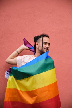 Uluslararası Gurur Ayı 'nı kutlayan gökkuşağı bayrağına sarılı eşcinsel adam.