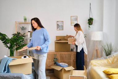 Yeni bir eve yerleşmek için hareket eden bir karton kutuda toplanan iki kadın. Öğrenci ikametgahı.