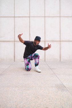 Genç adam gündelik giysiler giyip sokakta hip hop yapıyor.