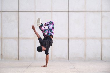 Siyah tişörtlü genç adam sokakta amuda kalkıyor.