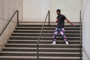 Genç adam şehrin merdivenlerinde dans ediyor.