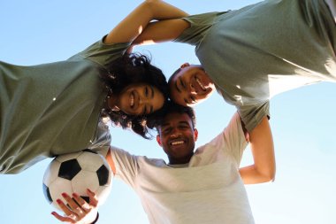 Futbol topunu tutarken bir araya toplanan üç mutlu futbolcu.