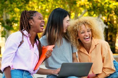 Üç mutlu çok ırklı arkadaş parkta çalışırken gülüyorlar..