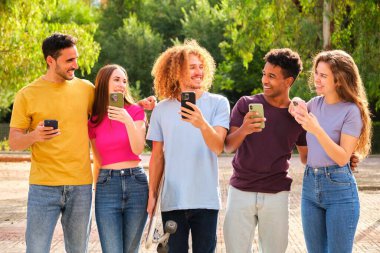 Bir grup arkadaş akıllı cep telefonlarını izliyor ve takılıyor, gençler yeni teknoloji eğilimlerine bağımlı..