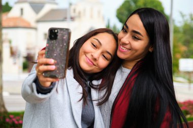 Mutlu Latin lezbiyen çift sokakta selfie çekerken sarılıyor. LGBT çifti.