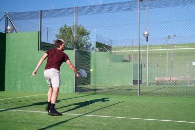 Erkek raket tenisçisi, forehand backhand voleybol sahasında geri dönen topu vuruyor.