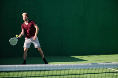 Kürek çeken genç sporcu raketle topu iade ediyor.