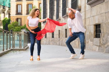 Genç dansçılar sokakta eğlenirken kırmızı peçeli Küba salsa dansları yapıyorlar.