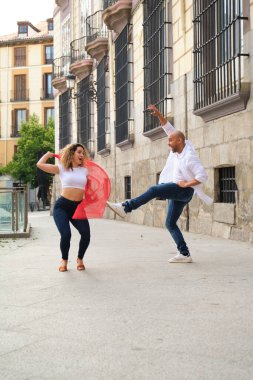 Genç dansçılar eski bir kasabanın sokaklarında Küba salsası yapıyorlar.