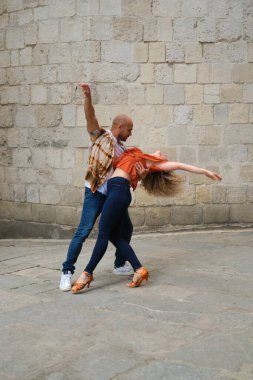 Genç çift, yaşlı bir duvarın önünde salsa yapıyor.