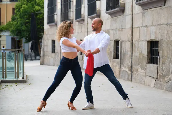 Genç dansçılar eski bir Avrupa şehrinin caddesinde Küba salsası yapıyorlar.