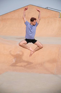 Genç erkek dansçı dışarıda çalışıyor, mavi tişört ve siyah şort giyiyor.