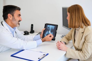 Doktor, kırık kalça ameliyatından önce kadın hastasına röntgeni açıklıyor. Sağlık ve İlaç Hizmetleri.