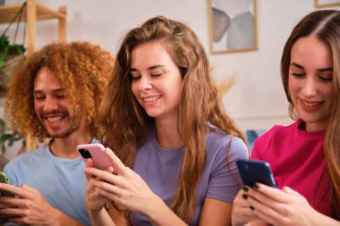 Grup gençleri ellerinde cep telefonlarıyla video izliyor, internetten iletişim kuruyor, paylaşılan dairede sohbet ediyorlar..