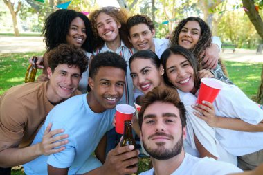 Bir grup arkadaş gülüyor ve parkta selfie çekerken eğleniyorlar.