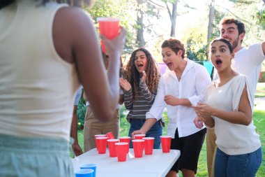 Neşeli gençler açık hava partisinde bira tenisi oynayarak eğleniyorlar.
