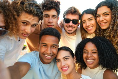 Bir grup yetişkin dışarıda selfie çekerken gülümsüyor.