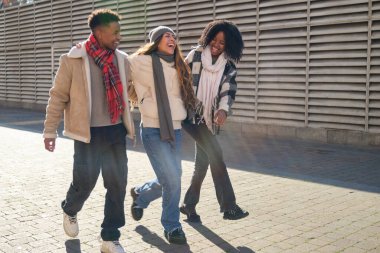 Neşeli, çoklu etnik arkadaşlardan oluşan bir grup güneşli bir kış gününde birlikte yürüyüş yapıyorlar.