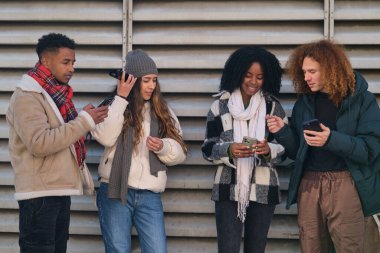 Dört çok ırklı öğrenci akıllı telefon kullanıyor, çevrimiçi içeriği paylaşıyor ve eğleniyor