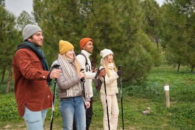 Yürüyüş direkleri kullanarak ormanda yürüyen bir grup yürüyüşçü.