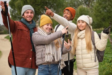 Akıllı telefon kullanan ve doğa yürüyüşünün tadını çıkaran bir grup genç yürüyüşçü.