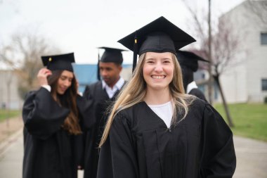 Sınıf arkadaşlarıyla mezuniyeti kutlayan neşeli bir üniversite öğrencisinin portresi.