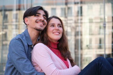 Güneşli bir günde kucaklaşan ve gülümseyen mutlu genç çift.