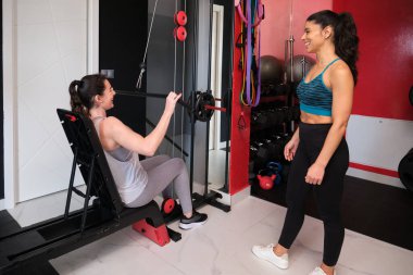 Bir kadın spor salonunda kişisel antrenörünün yardımıyla kablolu televizyon kullanıyor.