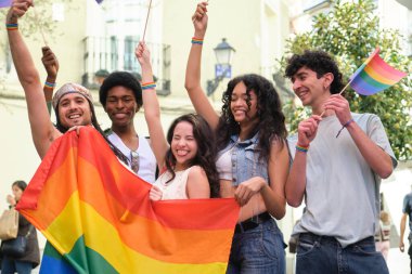 LGBT gururunu kutlayan gençler ellerinde gökkuşağı bayrağı sallıyor ve gökkuşağı bayrakları sallıyorlar.