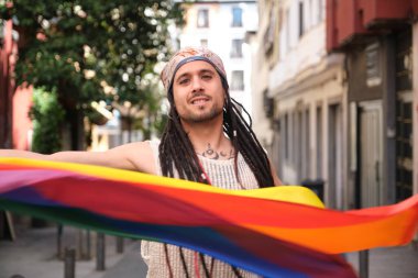 Elinde gökkuşağı bayrağı olan genç sanatçı LGBT gururunu kutluyor.