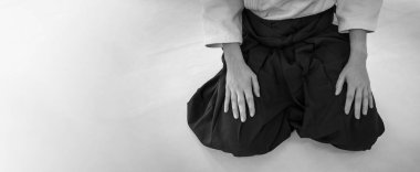 Dojo arka planında aikido dövüş sanatı pratiği yapan bir kadın. Nöbet konumu.